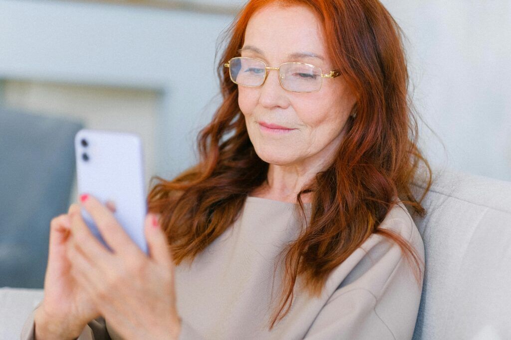 Idosa segurando um smartphone para fazer a validação por reconhecimento facial, conforme as novas regras do empréstimo consignado do INSS.