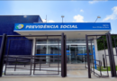 Fachada de uma agência oficial da Previdência Social com as portas de ferro fechadas sob a luz do dia, indicando a suspensão das atividades.